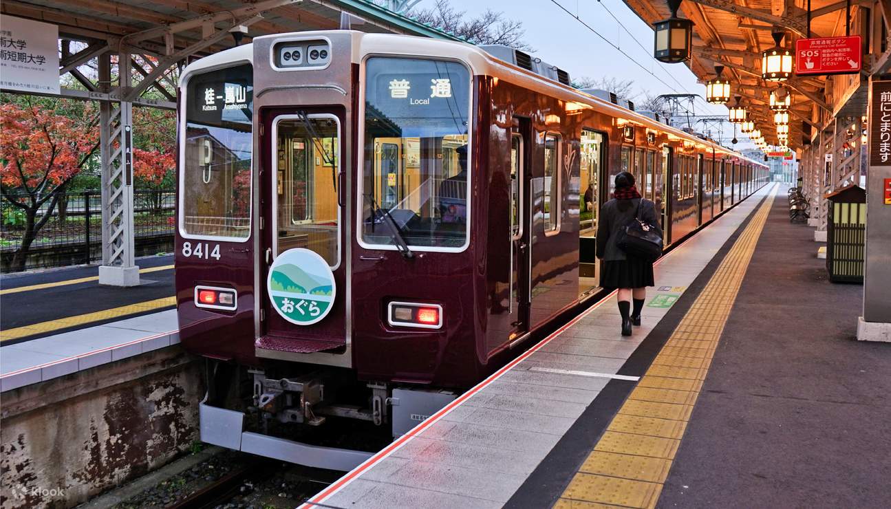 A maroon Hankyu train at a station platform, ready for departure